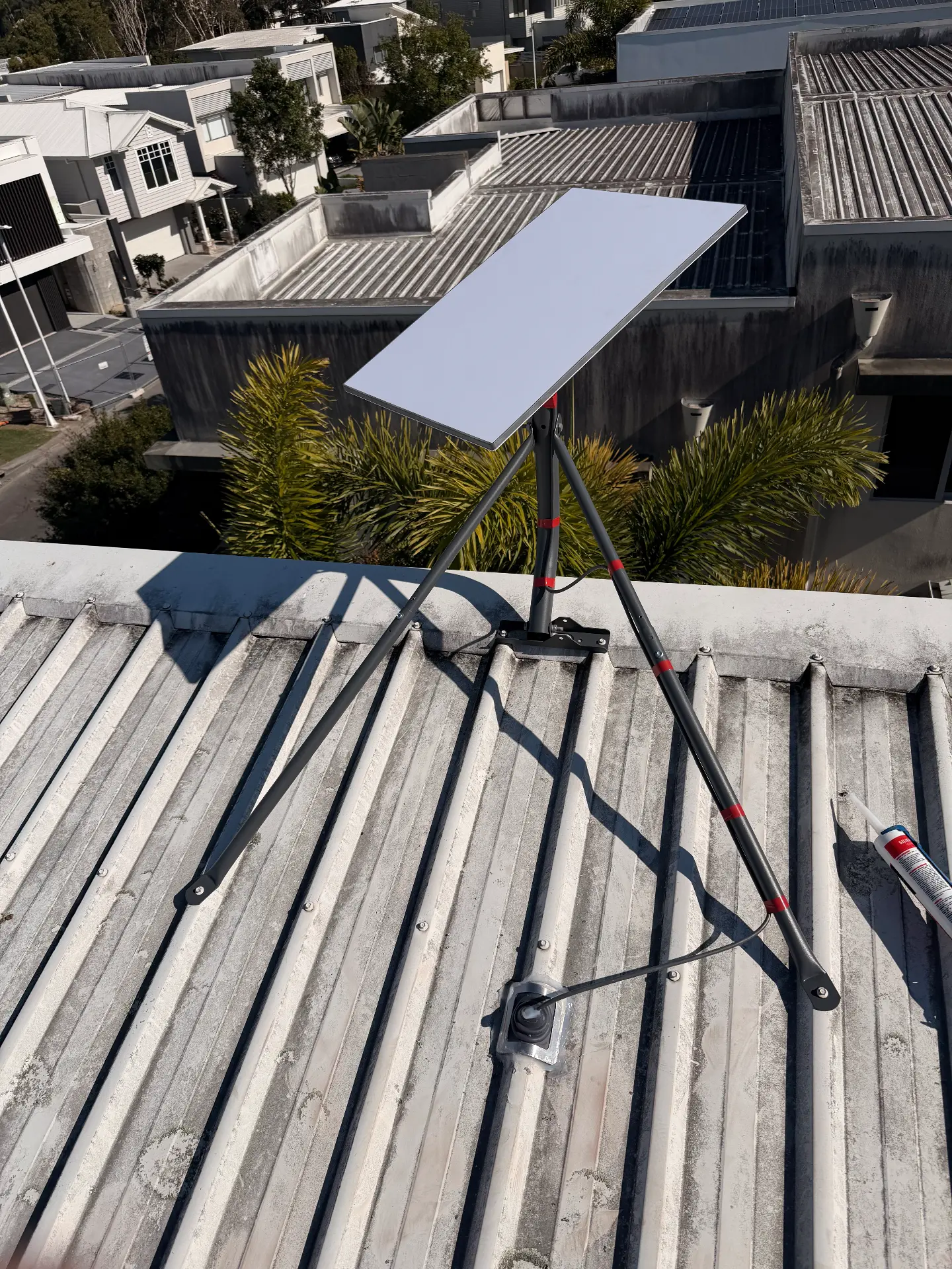 Starlink dish on a tripod mount fixed to a corrugated roof
