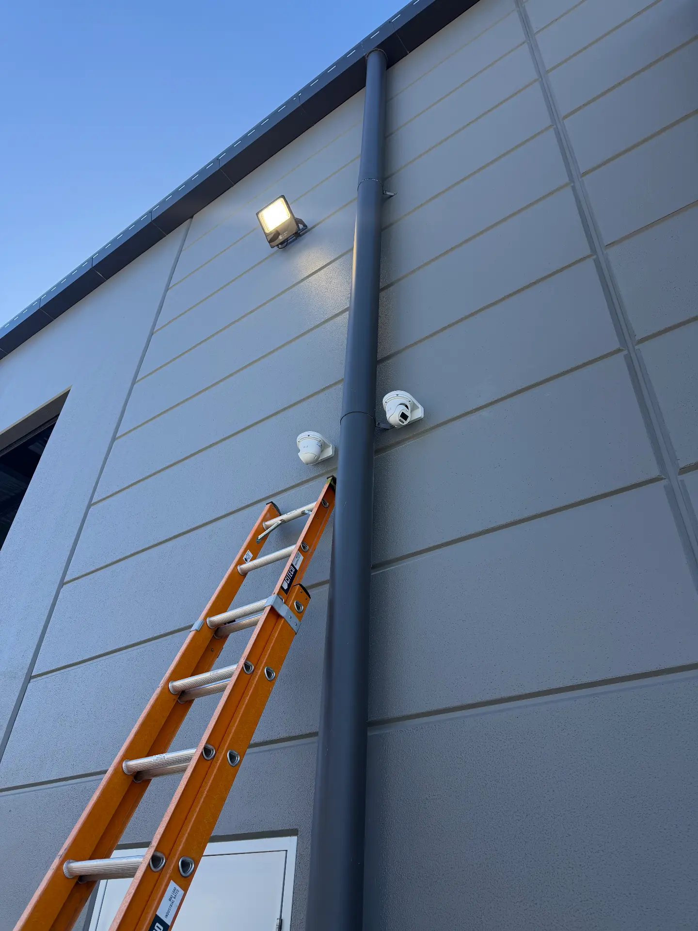 Two CCTV cameras mounted high on a commercial building facade